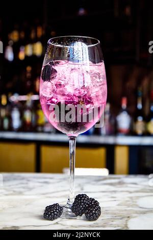 Cocktail mit Sekt, BlackBerry und Beerenlikör in einem Weinglas. Stockfoto