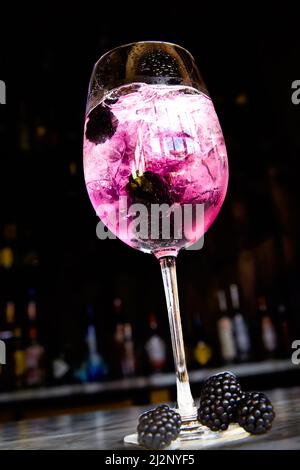 Cocktail mit Sekt, BlackBerry und Beerenlikör in einem Weinglas. Stockfoto
