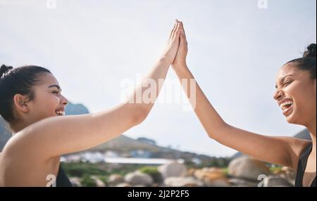 Workout, zerquetscht. Eine kurze Aufnahme von zwei attraktiven, sportlichen jungen Frauen, die während eines Trainings am Strand hochstechen. Stockfoto