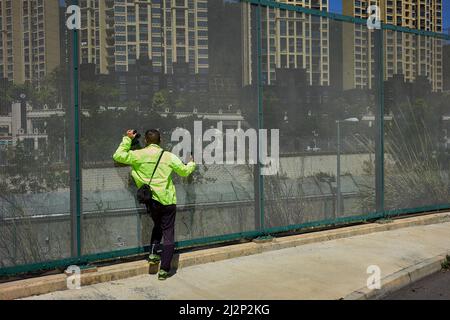 Hongkong, China. 03. April 2022. Ein Mann spricht, während er seine Verwandten durch ein Fernglas in Shenzhen über den Grenzzaun bei Heung Yuen Wai in Hongkong beobachtet. An der Grenze zwischen Hongkong und Shenzhen gelegen, ist Hung Yuen Wai einer der Orte, an dem Familien, die aufgrund von Reisebeschränkungen zwischen Covid-19 und der Grenze getrennt sind, einander sehen können. Kredit: SOPA Images Limited/Alamy Live Nachrichten Stockfoto