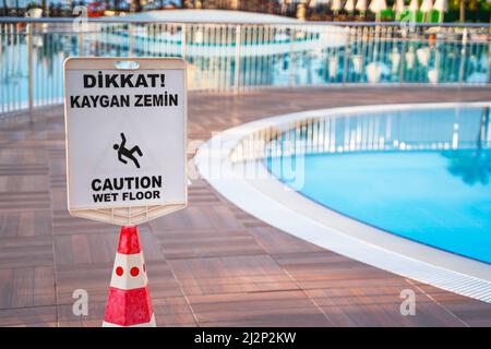 Warnschild am nassen Boden in der Nähe des Swimmingpools Stockfoto