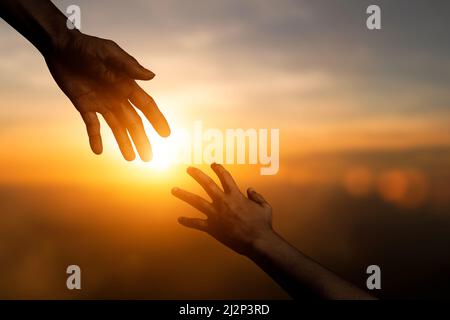 Silhouette des Erreichens, geben eine helfende Hand, Hoffnung und unterstützen sich gegenseitig über verwischen Sonnenuntergang Himmel Hintergrund. Konzept des internationalen Tag des Friedens und Stockfoto