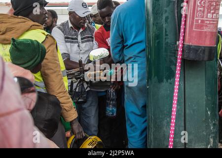 Nakuru, Kenia. 02. April 2022. Ein Angestellter füllt eine Plastikflasche mit Öl, während andere Motorradfahrer warten. Kenia ist von einem großen Ölmangel heimgesucht worden, mit langen Warteschlangen von Autofahrern, die darauf warten, in einigen Tankstellen bedient zu werden, die noch immer das notwendige gut haben. Kenya Energy and Petroleum Regulatory (EPRA) führte den Mangel auf beispiellose logistische Herausforderungen zurück. Die globalen Ölpreise sind nach dem Krieg zwischen Russland und der Ukraine, der den Preis auf ein 14-jähriges hoch getrieben hat, beeinflusst worden. (Foto von James Wakibia/SOPA Images/Sipa USA) Quelle: SIPA USA/Alamy Live News Stockfoto