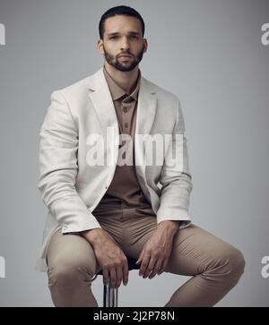 Ein gut geschnittener Anzug sorgt für grenzenloses Vertrauen. Aufnahme eines hübschen jungen Mannes, der tagsüber alleine im Studio sitzt. Stockfoto