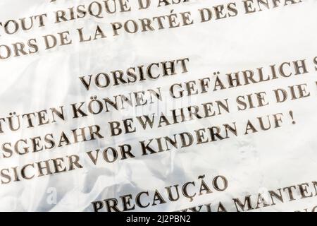 Warnung zur Erstickungsgefahr (Deutsch & mehrsprachig) auf LDPE-/Polyethylenbeutel mit geringer Dichte. Für Kinder-Sicherheitswarnung, Kunststoff-Recycling Stockfoto