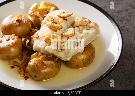 Portugiesischer Bacalhau a Lagareiro gesalzener Kabeljau in Öl gebacken mit Kartoffeln aus der Nähe in einem Teller auf dem Tisch. Horizontal Stockfoto