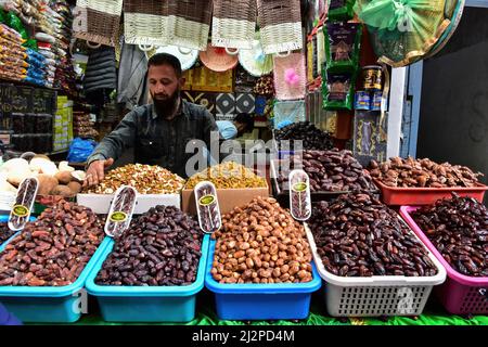 Srinagar, Indien. 03. April 2022. Ein Händler am Straßenrand verkauft Datteln und andere iftar-Artikel am ersten Tag des Ramadan in Srinagar. Muslime auf der ganzen Welt markieren den Monat Ramadan, den heiligsten Monat im islamischen Kalender, in dem Gläubige von Sonnenaufgang bis Sonnenuntergang fasten. Kredit: SOPA Images Limited/Alamy Live Nachrichten Stockfoto