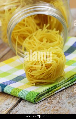 Ungekochte italienische Tagliatelle Nester auf buntem Küchentuch Stockfoto