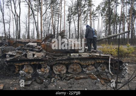 Kiew, Ukraine. 03. April 2022. Anwohner stehen auf einem zerstörten russischen Panzer während der russischen Invasion der Ukraine in Bucha, in der Nähe von Kiew, Ukraine am Sonntag, 3. April 2022. Foto von Vladyslav Musienko/UPI Credit: UPI/Alamy Live News Stockfoto