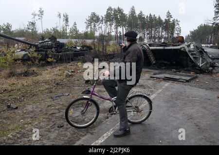 Kiew, Ukraine. 03. April 2022. Die Anwohner stehen neben einem zerstörten russischen Panzer, während der russische Angriff auf die Ukraine am Sonntag, den 3. April, in Bucha, in der Nähe von Kiew, der Ukraine, fortgesetzt wird. 2022. Foto von Vladyslav Musienko/UPI Credit: UPI/Alamy Live News Stockfoto