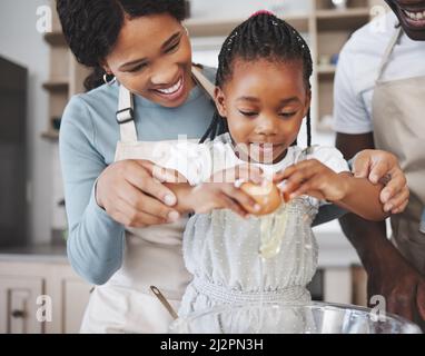 Die Welt, die wir entdeckt haben, liebt dich nicht wie deine Familie. Aufnahme eines Paares, das mit ihrer Tochter zu Hause backt. Stockfoto