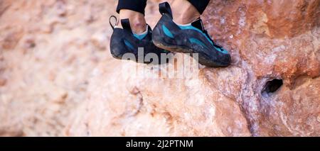 Füße mit Kletterschuhen auf den Felsen aus der Nähe. Stockfoto