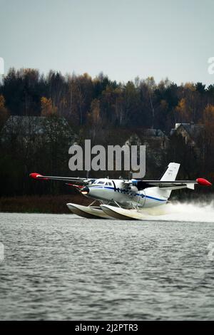 Das zweimotorige Wasserflugzeug ein Wasserflugzeug steigt aus dem Wasser, aus dem Waldsee, dem nördlichen Land auf. Wasserflugzeug Stockfoto