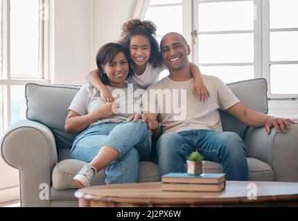 Wir freuen uns auf eine liebevolle, strahlende Zukunft. Aufnahme einer jungen Familie, die sich zu Hause entspannt. Stockfoto