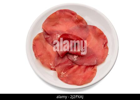 Bresaola della Valtellina - Italienische luftgetrocknete Rinderscheiben in weißen Teller isoliert auf weiß mit Schneideweg Stockfoto