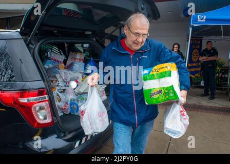 Warminster, Usa. 03. April 2022. Ein Freiwilliger transportiert Gegenstände während einer Food-Fahrt vom Polizeikreuzer in einen Lieferwagen, um die Lebensmittelregale der Warminster Food Bank am Sonntag, den 03. April 2022 in Gant in Warminster, Pennsylvania, aufzufüllen. Über 2300 Pfund Lebensmittel wurden zusammen mit Geschenkkarten und anderen Gegenständen gespendet. (Foto: William Thomas Cain/Alamy Live News Stockfoto
