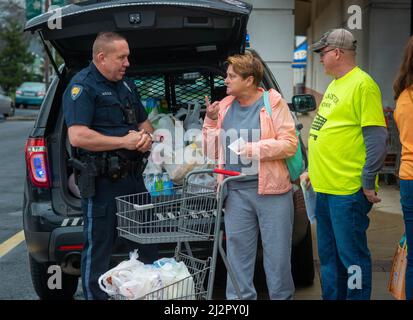 Warminster, Usa. 03. April 2022. Chris McCole (links), Polizeibeamter von Warminster, plaudert mit Linda Morrow (Mitte) und Brian Foedisch, während er während einer Lebensmittelaktion Spenden in das Polizeiauto einlädt, um die Lebensmittelregale der Warminster Food Bank am Sonntag, den 03. April 2022 bei Giant in Warminster, Pennsylvania, aufzufüllen. Über 2300 Pfund Lebensmittel wurden zusammen mit Geschenkkarten und anderen Gegenständen gespendet. (Foto: William Thomas Cain/Alamy Live News Stockfoto