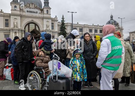 LVIV, UKRAINE - APR 02, 2022: Freiwillige und Flüchtlinge, die gerade mit dem Evakuierungszug aus Kramatorsk angekommen sind, warten auf ihre weitere Busverbindung Stockfoto