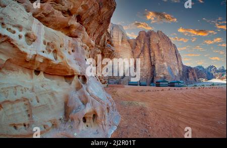 Zeltlager in Jordaniens Wadi Rum Wüste, umgeben von hohen roten Bergen und besucht von Kamelen Stockfoto