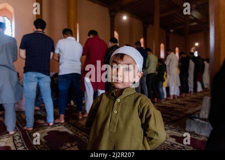 Srinagar, Indien. 03. April 2022. Ein muslimischer Junge aus Kaschmir sieht zu, wie Muslime am ersten Tag des Ramadan Mittagsgebete in Jamia Masjid anbieten. Der heiligste Monat des Islam Ramadan ist eine Zeit des intensiven Gebets, des Fastens von Sonnenaufgang bis Sonnenuntergang und der nächtlichen Feste. (Foto von Idrees Abbas/SOPA Images/Sipa USA) Quelle: SIPA USA/Alamy Live News Stockfoto