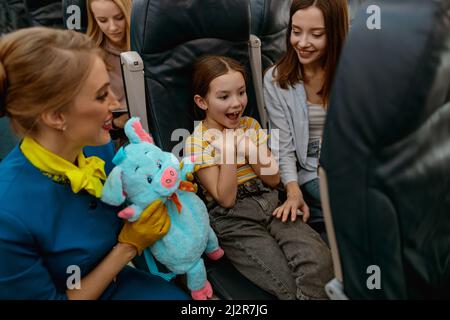 Glückliches Kind feiert Geburtstag mit Mutter und Stewardess im Flugzeug Stockfoto