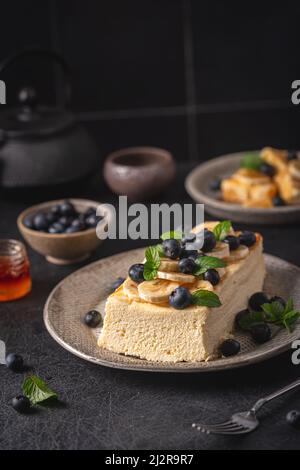 Hausgemachter Hüttenkäse Backen Kuchen Auflauf mit Beeren und Banane auf schwarzem Hintergrund Stockfoto