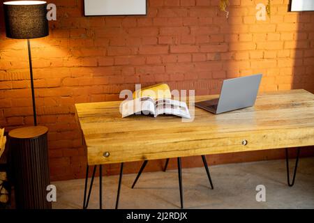 Stilvoller und gemütlicher Arbeitsplatz mit Holztisch zu Hause Stockfoto