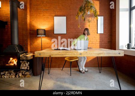 Frau sitzt am Tisch im Wohnzimmer im Loft-Stil Stockfoto