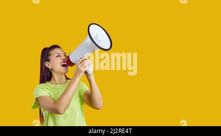 Glückliche junge Frau, die durch das Megaphon schreit und laut über den Verkauf ankündigt Stockfoto