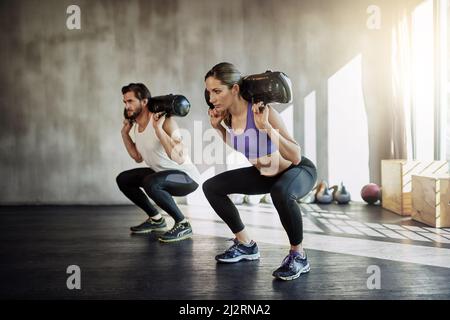 Es ist ein guter Tag, um etwas Schweres zu heben. Aufnahme von zwei jungen Menschen, die mit Gewichten im Fitnessstudio trainieren. Stockfoto