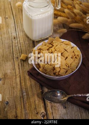 Ganze Körnerkissen, Milch in einem Krug und ein Haufen Getreide auf einem hölzernen Hintergrund. Schnelles Frühstück mit Cerealien. Leckeres gesundes Essen, Express-Frühstück, VI Stockfoto
