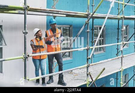 Die Zukunft des Bauens mit Hilfe von smarten Apps gestalten. Aufnahme eines jungen Mannes und einer jungen Frau mit einem digitalen Tablet während der Arbeit an einer Baustelle Stockfoto