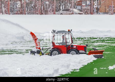 Riga, Lettland - 03. April 2022: Arbeiten des Schneereinigers auf dem Fußballstadion. Stockfoto