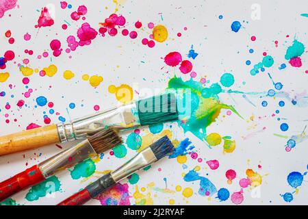Künstlerische Pinsel auf dem Hintergrund von bemaltem Papier mit hellen Flecken und Spritzer, Kunstkonzept Stockfoto