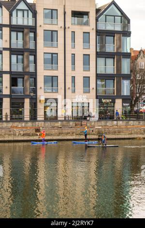 Danzig Polen März 2022 Gruppe von Sup-Surfern stehen auf Paddle-Board, Frauen stehen auf Paddeln zusammen in der Stadt Motlawa Fluss und Kanal in der Altstadt Danzig Polen. Tourismusattraktion Aktive Erholung im Freien Soziale Distanzierung Reiseziele Stockfoto