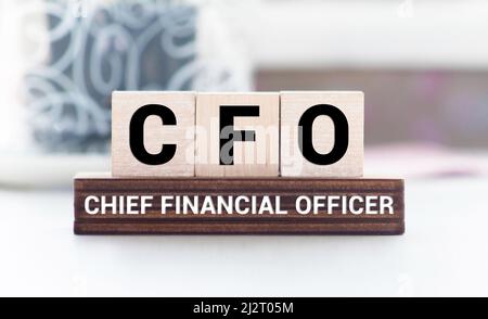 CFO Chief Financial Officer auf einem Holzwürfel vor einem Laptop geschrieben. Stockfoto