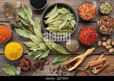 Schüsseln mit verschiedenen Gewürzen - roter Paprika, Paprika, Anise, Safran, schwarze Samen, Muskatnuss, Kardamom-Schoten, Thymian, Handschuhe, Kurkuma, Zimt, Lorbeer. Diff Stockfoto