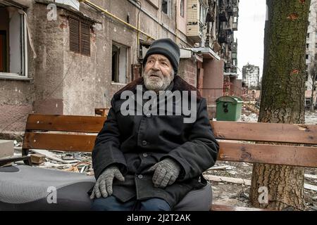 Mariupol, Ukraine. 03. April 2022. Ein traumatisierter Zivilist sitzt auf einer Bank außerhalb seines ausgebombten Wohnblocks. Der Kampf zwischen Russland und der Ukraine unter der Führung des Asow-Bataillons wird in der Hafenstadt Mariupol fortgesetzt. Kredit: SOPA Images Limited/Alamy Live Nachrichten Stockfoto