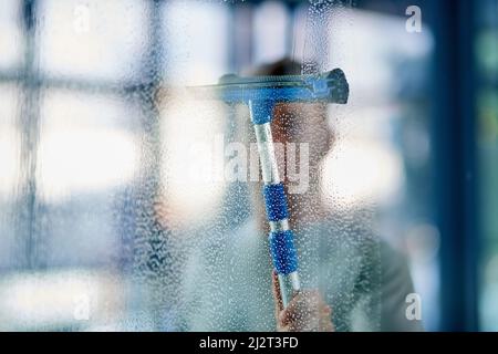Sauber und hygienisch. Aufnahme eines jungen Mannes, der die Fenster im Büro putzte. Stockfoto