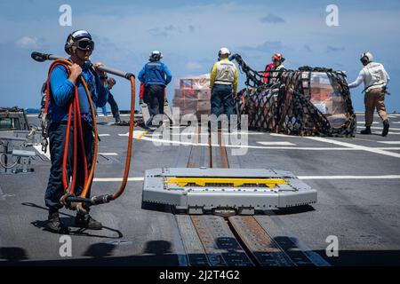 220330-N-TT059-2044 SÜDCHINESISCHES MEER (MÄRZ 30, 2022) USA Die Matrosen der Marine handhaben Fracht und Ausrüstung während der Vertical Replenishment (VERTREP)-Operationen an Bord des Lenkraketen-Zerstörers USS Momsen (DDG 92). Momsen ist Kommandant der Task Force 71/Destroyer Squadron (DESRON) 15, der größten vorwärtseingesetzten DESRON der Marine und der wichtigsten Kampftruppe der US-7.-Flotte, und unterstützt derzeit einen freien und offenen Indo-Pazifik-Raum. (USA Navy Foto von Mass Communication Specialist 3. Klasse Lily Gebauer) Stockfoto