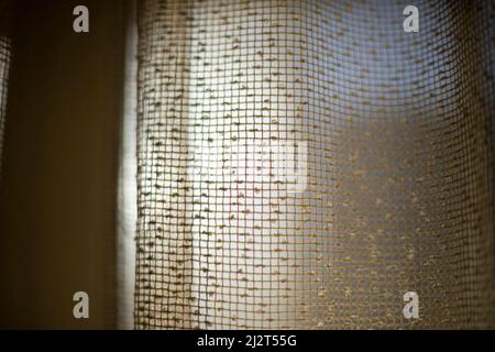 Vorhänge am Fenster. Licht durch Vorhänge. Struktur aus feinem Gitter. Falten aus Stoff. Stockfoto
