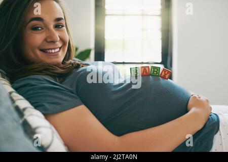 Ich kann es kaum erwarten, den Kleinen zu treffen. Aufnahme einer jungen Frau mit Babyblöcken auf ihrem schwanger Bauch. Stockfoto