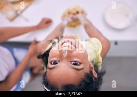 Sie freut sich am meisten, wenn sie in der Küche hilft. Kurzer Schuss eines entzückenden kleinen Mädchens, das zu Hause mit ihrer Mutter backt. Stockfoto