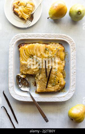 Eine Birne auf den Kopf gestellt Kuchen mit einer Portion auf einem Teller darüber. Stockfoto