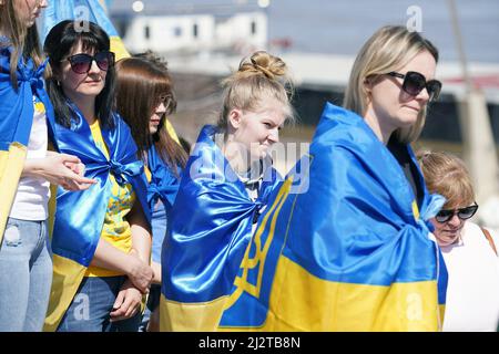 St. Louis, Usa. 03. April 2022. Am Sonntag, den 3. April 2022, hören Frauen Reden, während sie mit einer ukrainischen Flagge auf den Stufen des Gateway Arch in St. Louis gewickelt sind. Die ukrainische Gemeinschaft versammelte sich am Bogen mit gespendeten Stofftieren, die die Hunderte von Kindern darstellen, die während der aktuellen russischen Invasion getötet wurden. Die Versammlung umfasste Worte der Ermutigung, Gebete und ukrainische Musik. Foto von Bill Greenblatt/UPI Credit: UPI/Alamy Live News Stockfoto