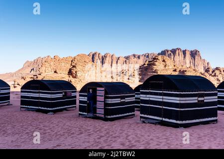 Ein junger Mann steht an der Tür Eines beduinisch-stilen Zeltes in der Wadi Rum Desert, Jordanien, Asien. Stockfoto