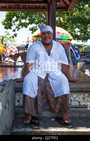 Balinesischer Mann in Goa Lawah, Bali, Indonesien, gekleidet für eine Zeremonie im bat Cave Tempel. Stockfoto