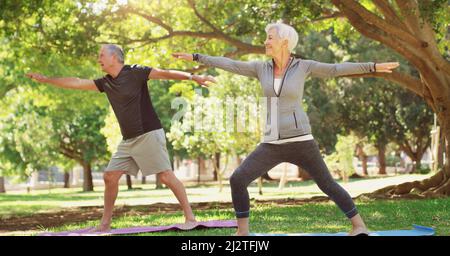 Es gibt keinen Pensionsplan, um zu arbeiten. Die ganze Aufnahme eines glücklichen Seniorenpaares, das gemeinsam im Park Yoga macht. Stockfoto