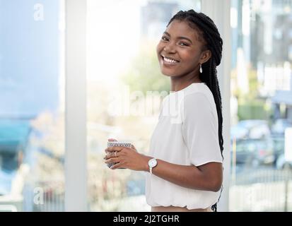 Etwas Kaffee, um mich durch den Tag zu bringen. Aufnahme einer jungen Geschäftsfrau, die bei der Arbeit eine Tasse Kaffee trinkt. Stockfoto