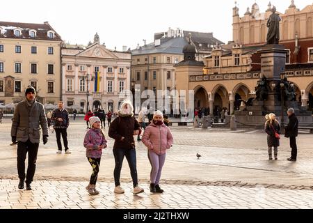 Krakau, Polen. 03. April 2022. Eine ukrainische Familie geht auf dem Hauptmarkt in Krakau spazieren, da die meisten Besucher dieser UNESCO-Stätte nun Ukrainer sind. Der Konflikt zwischen der Ukraine und Russland wird voraussichtlich bis zu 5 Millionen Ukrainer zur Flucht zwingen. Viele der Flüchtlinge suchen in Polen Asyl. Die meisten karitativen Hilfen in Polen werden von Einzelpersonen, NGOs und Unternehmen geleistet. Nach einem Monat des Konflikts sucht Polen nach Möglichkeiten, ukrainische Flüchtlinge zu integrieren und Polen und Ukrainern Raum für Kontakt und Zusammenarbeit zu bieten. Kredit: SOPA Images Limited/Alamy Live Nachrichten Stockfoto